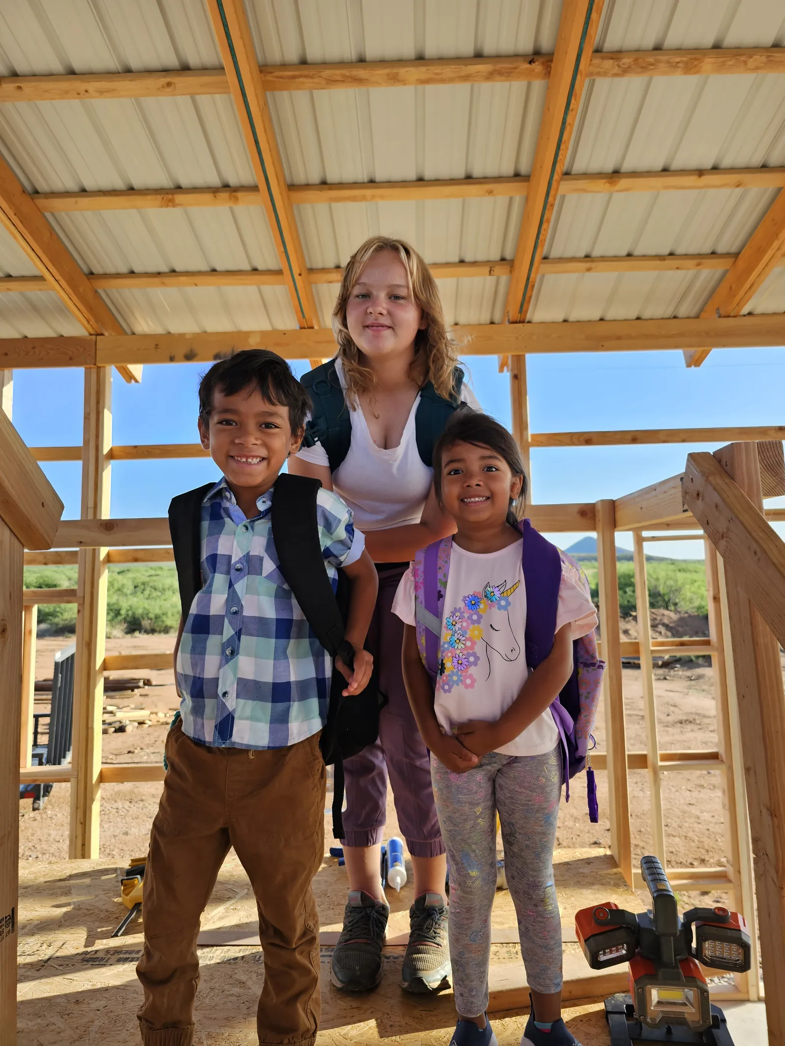 Three kids standing inside the timber framing of our off-grid home build