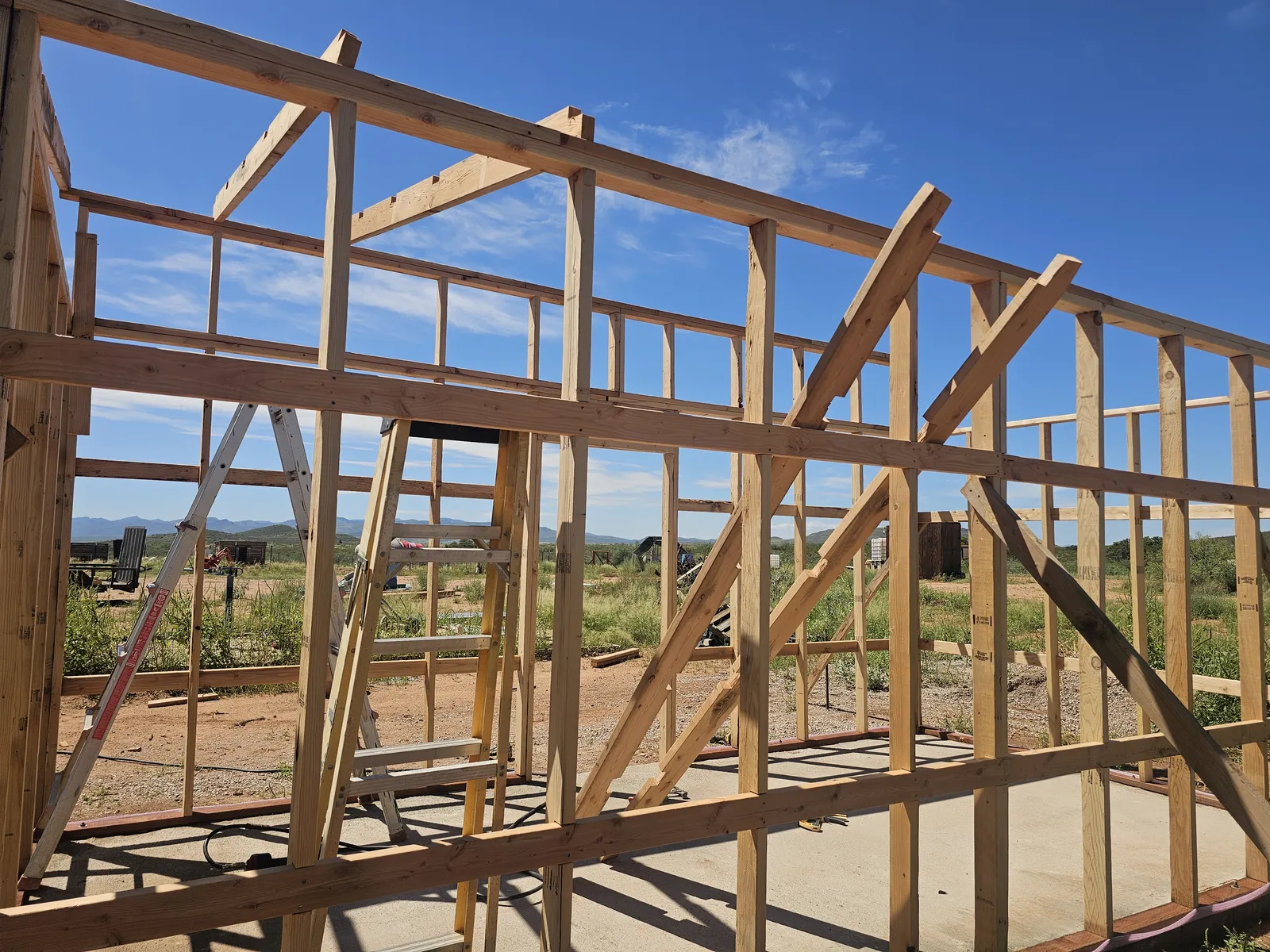 Bare wood wall framing of the shed against a blue sky with open desert behind it