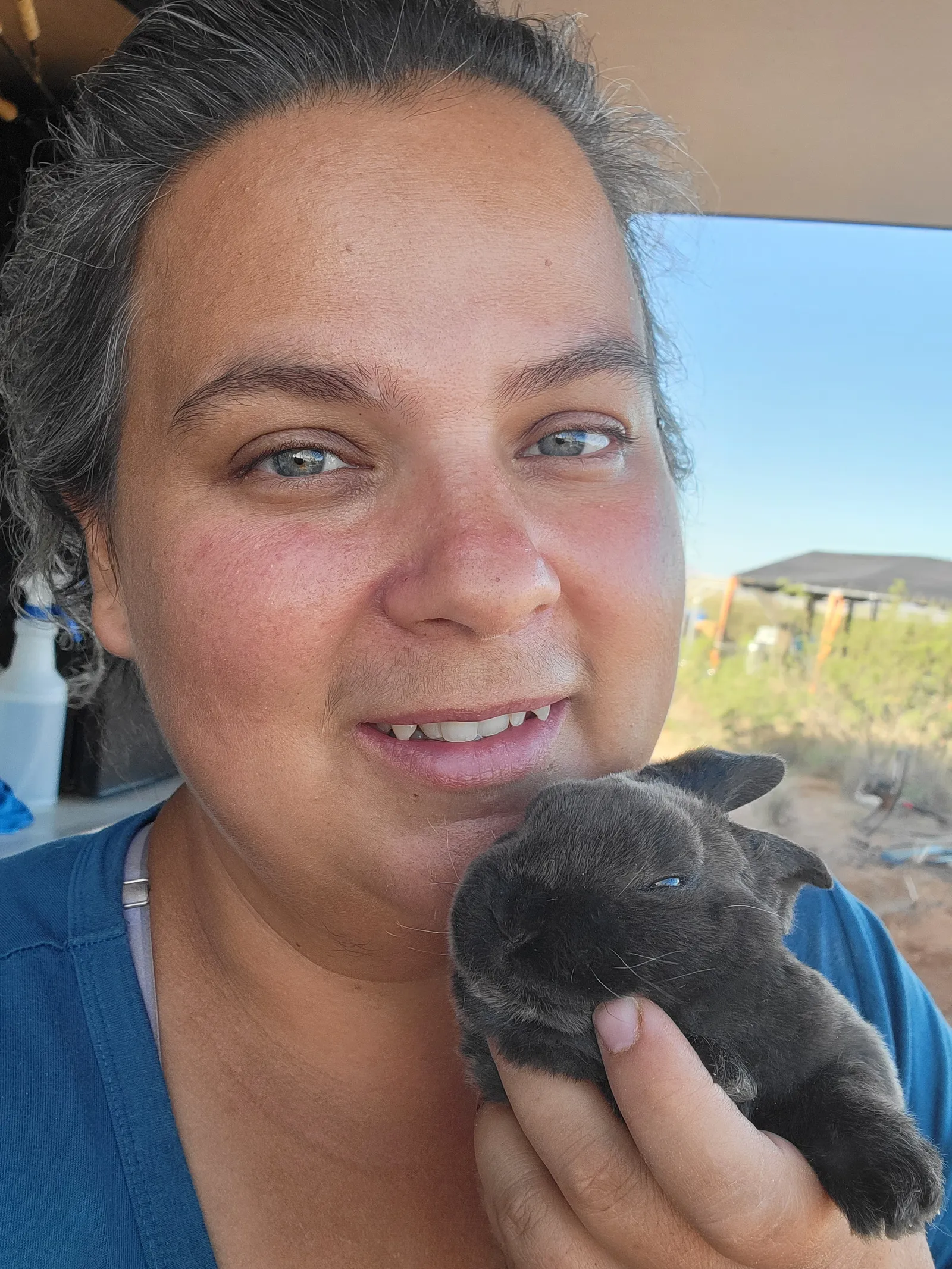 Smiling woman holding a small dark gray rabbit